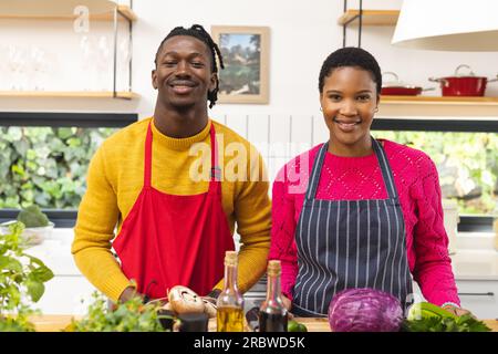 Ritratto di una felice coppia afroamericana in grembiuli in cucina Foto Stock