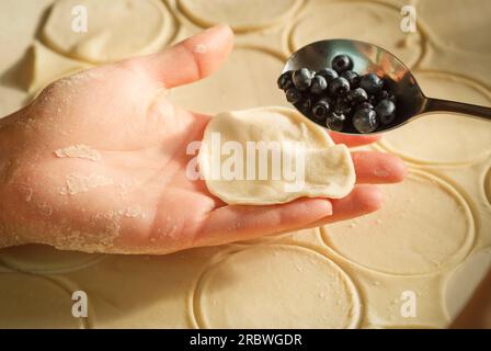 fai pierogi varenky ai gnocchi di mirtilli a casa tua, passo dopo passo. Processo di preparazione del tradizionale polacco estivo o piatto ucraino con farina e frutta Foto Stock