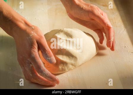 Le mani fanno l'impasto. Fai pierogi varenky ai gnocchi di mirtilli a casa tua, passo dopo passo. Processo di preparazione tradizionale polacco estivo o piatto ucraino wi Foto Stock