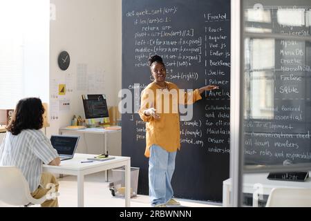 Insegnante afroamericano che indica la lavagna con informazioni e LE insegna agli studenti Foto Stock