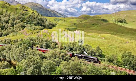 Treno a vapore Jacobite in viaggio attraverso le verdi colline e montagne verso Mallaig, sulla costa occidentale della Scozia Foto Stock