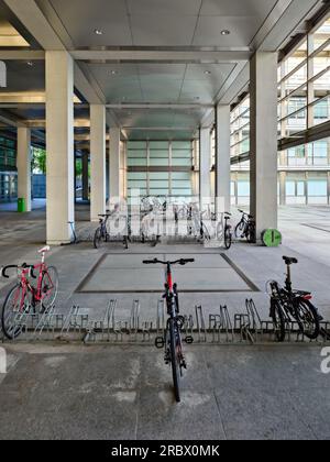 Portabiciclette del campus universitario vicino a edifici di architettura moderna, niente persone. Foto Stock