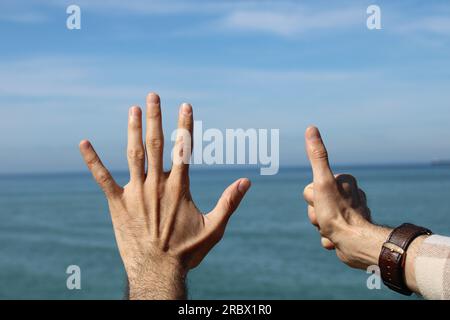 Fare mano, mostrando il simbolo del gesto numero sei su sfondo blu estate cielo natura. Numero di gesture 6. Numero sei nella lingua dei segni. sesto, conteggio do Foto Stock