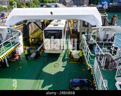 Alfa Travel tour bus in uscita dal traghetto CalMac mentre i lavoratori sono in attesa, Oban, Scozia, Regno Unito. Foto Stock