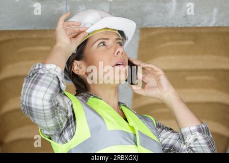 donna ingegnere con elmetto di sicurezza che parla al telefono Foto Stock