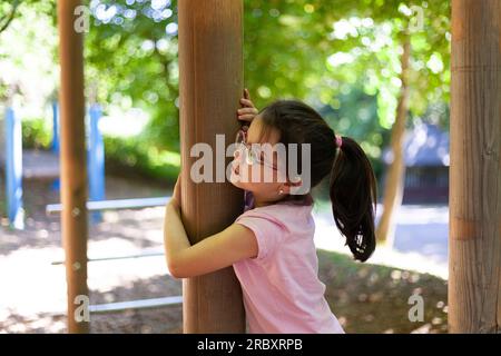 Ritratto di una graziosa bambina con occhiali sul parco giochi in estate Foto Stock