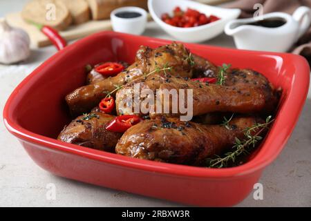 Cosce di pollo glassate in salsa di soia con sesamo nero, peperoncino e timo su un tavolo leggero, primo piano Foto Stock