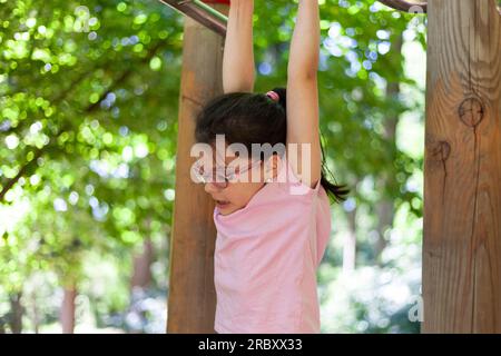 Bambina asiatica che gioca nel parco giochi del parco. Bambini che si divertono all'aperto. Foto Stock