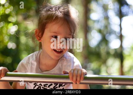 Bambina carina che si diverte nel parco giochi del parco. Foto Stock