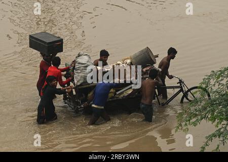 Nuova Delhi, Delhi, India. 11 luglio 2023. Una famiglia spinge un carrello per biciclette con i suoi effetti personali dopo essersi trasferita da zone basse vicino al fiume Yamuna dopo che è fuoriuscito a causa delle forti piogge a nuova Delhi, in India. (Immagine di credito: © Kabir Jhangiani/ZUMA Press Wire) SOLO USO EDITORIALE! Non per USO commerciale! Foto Stock