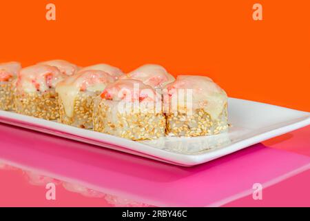 Sushi, panini con caviale, gamberi, tonno e avocado e formaggio Philadelphia, su un piatto bianco. Su uno sfondo colorato. copia spazio Foto Stock