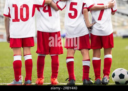 Gruppo di ragazzi scolastici in squadra sportiva. Boys Huddling in campo laterale durante il torneo. Maglia da calcio - bambini Foto Stock