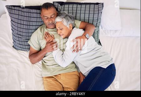Vista dall'alto, abbraccio da letto e coppia anziana, dormire e sposarsi con pace, rapporto e pensione. Romanticismo, vecchio e anziano in una camera da letto Foto Stock