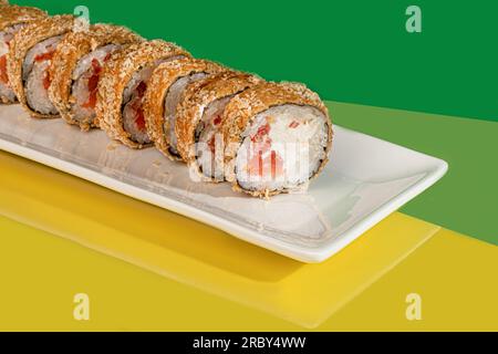 Sushi, panini con caviale, gamberi, tonno e avocado e formaggio Philadelphia, su un piatto bianco. Su uno sfondo colorato. copia spazio Foto Stock