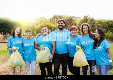 Volontari felici che aiutano la comunità a pulire e riciclare la plastica nella città del parco naturale - persone di diverse età ed etnia lavorano insieme per l'ambiente Foto Stock