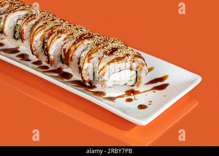 Sushi, panini con caviale, gamberi, tonno e avocado e formaggio Philadelphia, su un piatto bianco. Su uno sfondo colorato. copia spazio Foto Stock