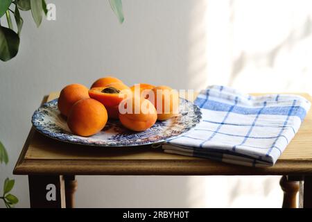 Albicocche fresche mature su tavola di legno, mattinata di sole, atmosfera da villaggio, rustica. Interni accoglienti. Concetto di raccolto. Mucchio di orano succoso Foto Stock