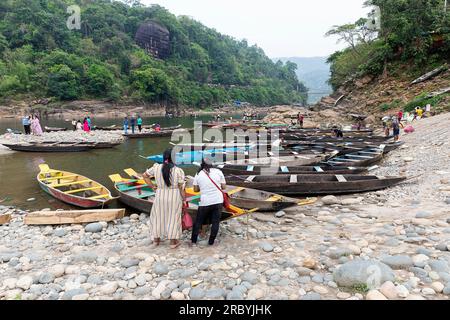 Turisti indiani che guardano le tradizionali barche di legno sulla riva di un fiume Umngot vicino al villaggio dawki a meghalaya, india Foto Stock
