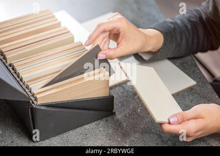 Una designer di interni donna sceglie un campione di colore da truciolato. Scelta del materiale in legno per il progetto d'interni, da truciolato a legno naturale Foto Stock