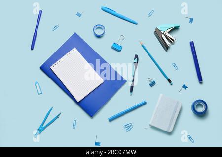 Composizione con notebook vuoto e materiali di consumo per cancelleria su sfondo blu Foto Stock