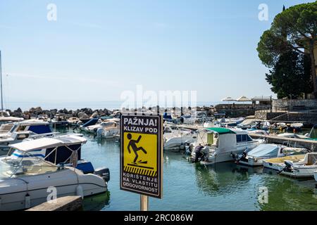 Opatija, Croazia. 10 luglio 2023. un segnale di avvertimento del pericolo di caduta sul molo del porticciolo cittadino Foto Stock