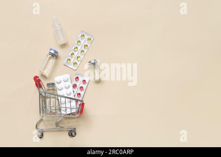 Mini carrello con diversi farmaci su sfondo beige Foto Stock