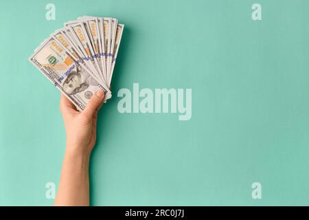 Un sacco di banconote da 100 dollari in mano sono piegate in un ventilatore su sfondo verde, vista dall'alto con spazio per il testo. Moneta, banconote in mani femminili Foto Stock