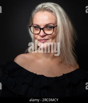 Bella donna bionda con gli occhiali sorridente Foto Stock