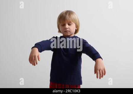 Ragazzo in pigiama che dorma su sfondo bianco Foto Stock