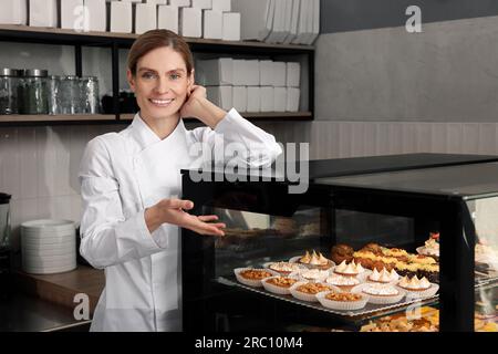 panettiere professionale vicino alla vetrina con pasticceria in negozio Foto Stock