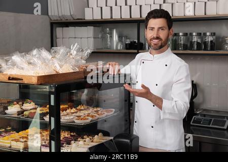 panettiere professionale vicino alla vetrina con pasticceria in negozio Foto Stock