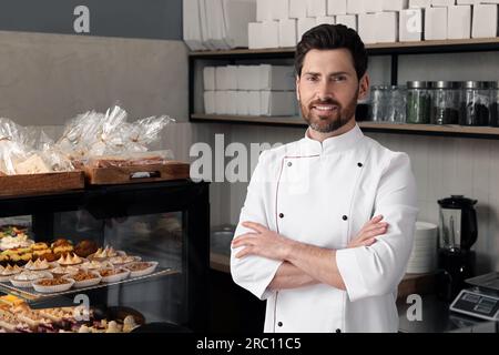 panettiere professionale vicino alla vetrina con pasticceria in negozio Foto Stock