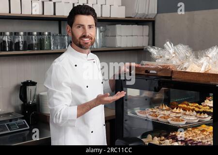 panettiere professionale vicino alla vetrina con pasticceria in negozio Foto Stock