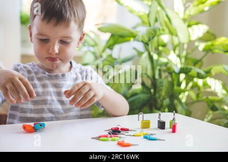 Il bambino lavora con materiale Montessori con serrature colorate. Raccoglie i tasti. Sviluppa le abilità motorie fini. Foto Stock