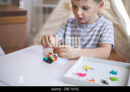 Il bambino lavora con materiale Montessori con serrature colorate. Raccoglie i tasti. Sviluppa le abilità motorie fini. Foto Stock