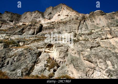 Un turista è visto su una scala che conduce alle antiche abitazioni della città grotta di Vardzia, Georgia Foto Stock