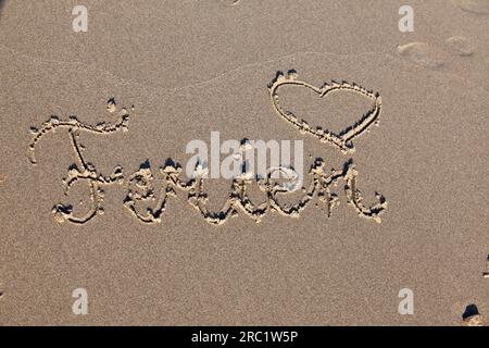 Cuore attirato dalla sabbia sulla spiaggia con le parole Holiday Foto Stock