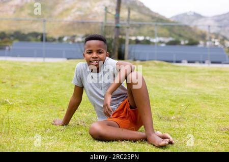 Ritratto di uno studente afroamericano seduto sull'erba a scuola Foto Stock