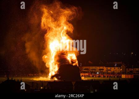 La gente assiste all'incendio del falò lealista di Craigyhill a Larne, Co Antrim, l'undicesima notte. Inaugurazione della dodicesima commemorazione. Data foto: Mercoledì 12 luglio 2023. Foto Stock