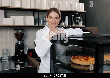 panettiere professionale vicino alla vetrina con pasticceria in negozio Foto Stock