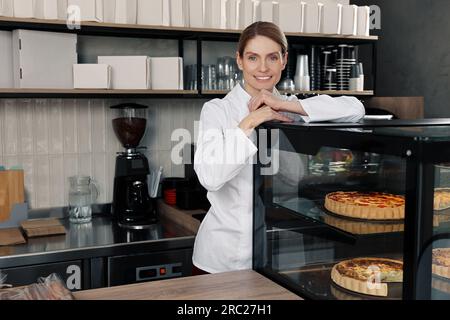 panettiere professionale vicino alla vetrina con pasticceria in negozio Foto Stock