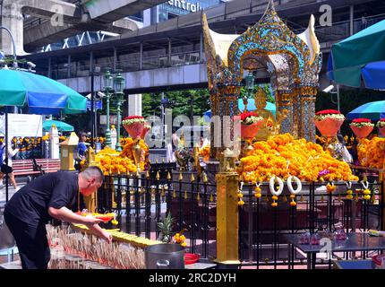 Un uomo presenta offerte al santuario di Erawan, un santuario indù all'incrocio di Ratchaprasong in Ratchadamri Road nel sottodistretto di Lumphini, Bangkok, Thailandia. Foto Stock