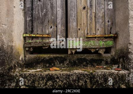 La porta sotto una vecchia porta di legno in uno storico edificio residenziale abbandonato nel villaggio di Trava, nel quartiere Lauco, Udine, Friuli, ne Italia Foto Stock