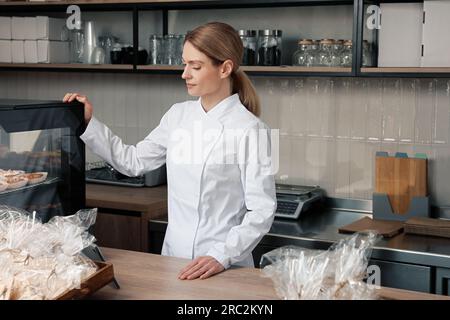 panettiere professionista alla cassa vicino alla vetrina in negozio Foto Stock