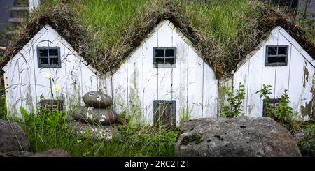 Tre piccole case di elfi bianchi in legno con tetto in muschio verde, tipiche dell'Islanda. Foto Stock