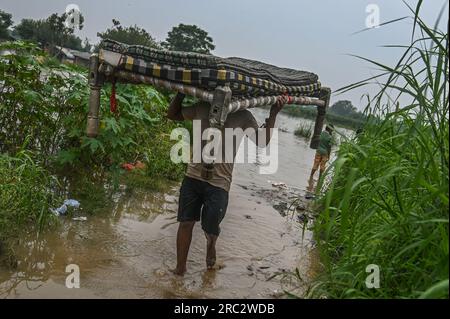 Nuova Delhi, Delhi, India. 11 luglio 2023. Un uomo trasporta un letto dopo essersi trasferito da aree basse vicino al fiume Yamuna dopo che è fuoriuscito a causa delle forti piogge a nuova Delhi, in India, l'11 luglio 2023. (Immagine di credito: © Kabir Jhangiani/ZUMA Press Wire) SOLO USO EDITORIALE! Non per USO commerciale! Foto Stock