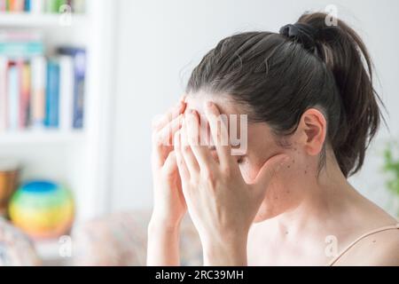 Giovane donna caucasica adulta con le mani che le coprono il viso. Immagine concettuale. Concetto di dolore o disagio fisico o psicologico. Copia spazio Foto Stock