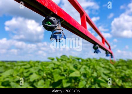 Sprinkler sulla staffa dell'irroratrice per protezione delle piante che si preparano a spruzzare un prodotto di protezione delle colture su un campo seminato con girasoli. Foto Stock