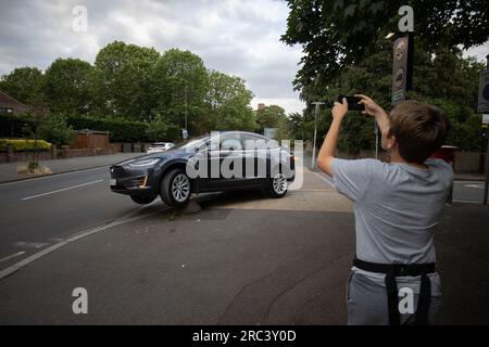 Tesla rimane intrappolata dopo aver guidato accidentalmente su un dissuasore stradale all'angolo di una strada residenziale a South Wimbledon, Londra, Inghilterra, Regno Unito Foto Stock