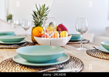 Primo piano su un tavolo da pranzo, frutta tropicale in ciotola servita con vetro vuoto e piatti per la cena di famiglia a casa Foto Stock
